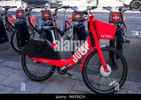 Uber rot Springen e-Bike neben Santander Zyklen, London, England, Großbritannien links Stockfoto