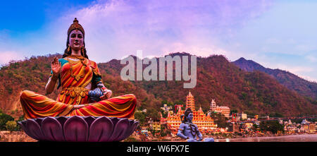 Der Ganges, die berühmte Brücke Laxman Jhula, umgeben von Tempeln und Bergen in Rishikesh, Indien Stockfoto