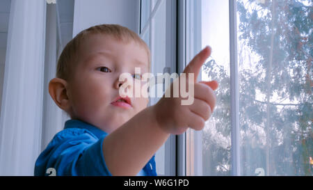 Nachdenkliche kleine Junge Blick durch Fenster Stockfoto