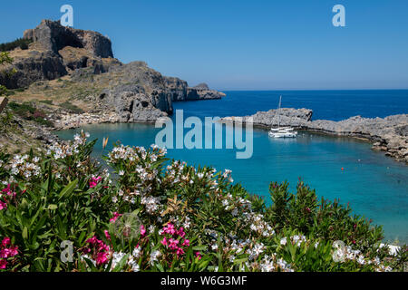 Griechenland, Rhodos, die größte der Dodekanes Inseln. St. Paul's Bay mit der Akropolis von Lindos in der Ferne mit dem Tempel der Athena Lindia. Stockfoto