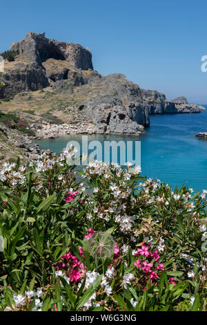 Griechenland, Rhodos, die größte der Dodekanes Inseln. St. Paul's Bay mit der Akropolis von Lindos in der Ferne mit dem Tempel der Athena Lindia. Stockfoto