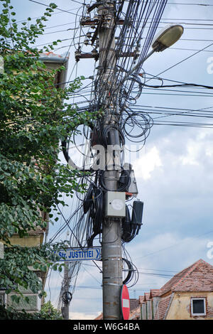 Straße Pol mit TV, Internet, Telefonie, Strom und Kabel hängend in einer unorganisierten Materie - in Justice Street (Strada Justitiei) in Si Stockfoto