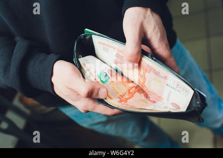 Hände nehmen Sie russische Rubel aus der Brieftasche. Nahaufnahme auf die Hände eines Menschen, wie er ist, eine Banknote aus seiner Brieftasche. Stockfoto