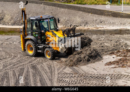 JCB zurück Hacke Reinigung einen Strand. Stockfoto