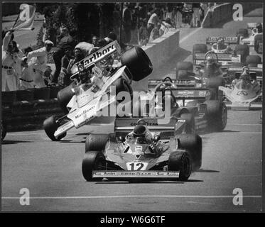 Uns Formel 1 Grand Prix, 1977, Long Beach Kalifornien mit der späten Driver James Hunt von England (gestorben 1993), World Champion F1 Fahren auf einem Rad nach der ersten Runde Unfall in der ersten Kurve Ecke mit 4 Rädern, Tyrell, hinter #12 Ferrari von Gilles Villeneuve (1982 gestorben) von Kanada, Sieger hatte von angetriebenen - Mario Andretti - Jagd war aus dem Rennen aus diesem Kontakt in seinem McLaren, aus original 8 x 10 Drucken scannen. James Simon Wallis Jagd war ein britischer Rennfahrer, der die Formel-1-Weltmeisterschaft 1976 gewann. Nach seinem Ausscheiden aus dem Rennsport 1979, Hunt wurde zu einem Medienkommentator und Busin Stockfoto