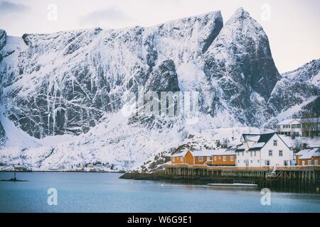 Traditionelle norwegische Holzhaus rorbu am Ufer auf den Fjord und die Berge in der Ferne zu stehen. Lofoten. Norwegen. Stockfoto