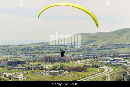 Fliegen über Stadt - ein Gleitschirm fliegen hoch über dem Highway 6 an der Stadt der Goldenen, mit Jefferson County Government Center im Hintergrund unten. CO, USA. Stockfoto