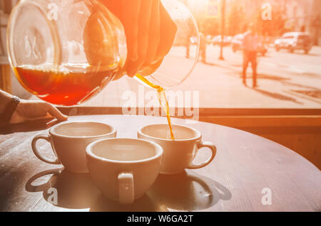 Barista gießen Kaffee aus der Chemex in die keramische weiße Tasse. Café Terrasse Stockfoto