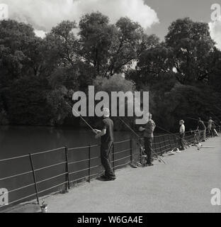 1960, historische, junge Burschen Angeln auf dem Serpentine Brücke am See Serpentine Lake im Hyde Park, London, UK. Stockfoto