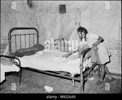 Tochter von Lawson Mayo, Behinderte Miner, macht das Bett in den vier Zimmer Haus, das die zwei Erwachsene und 10 Kinder zu Hause anrufen. Mullens Smokeless Coal Company, Mullens Mine, Harmco, Wyoming County, West Virginia. Stockfoto