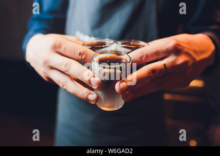 Männliche Hände jubeln mit Brille der Schuß oder Likör. Freunde trinken erschossen oder Likör und Prost. Männliche Hände jubeln mit Alkohol auf unscharfen bar Hintergrund Stockfoto