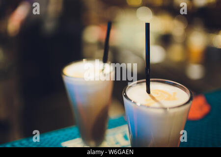 Zwei köstliche dickes Eis Milchshakes garniert mit Schokolade und Minze und in hohen gekühlte Gläser serviert auf einem kleinen alten hölzernen Fach. Stockfoto