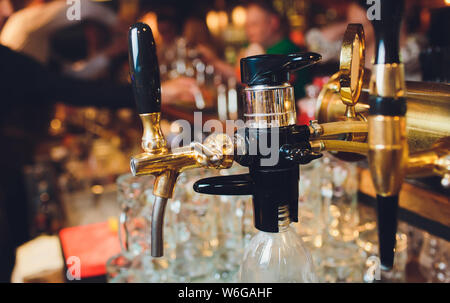 Das Bier in einem Pub. Tippt niemand. Selektive konzentrieren. Alkohol Konzept. Vintage Style. Bier Handwerk. Bar Tisch. Stahl Armaturen. Glänzende Gewindebohrer. Stockfoto