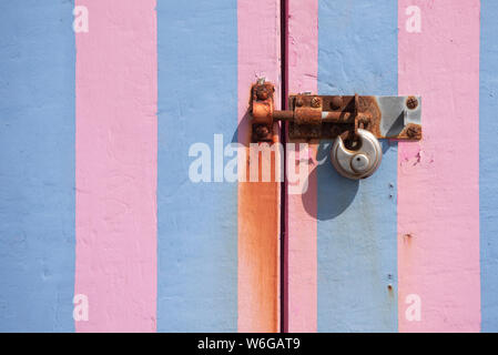 Bunt gestreiften Beach Hut Türen und rostige Vorhängeschloss Stockfoto
