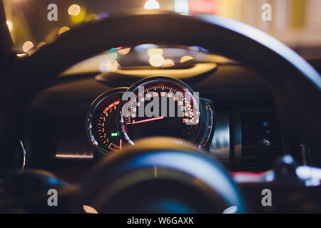 Tachometer zählen hohe Geschwindigkeit in einer schnellen Bewegung. Sportliches Fahrzeug die Zusatzinstrumente bei Nacht beleuchtet. Drehzahlmesser. Modernes Fahrzeug Cluster. Stockfoto