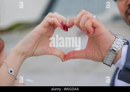 Heart-shaped Hand auf das Bokeh Hintergrund. Der Teenager faltete ihre Hände in die Form eines Herzens vor dem Hintergrund. glückliches Paar, Herz wi Stockfoto