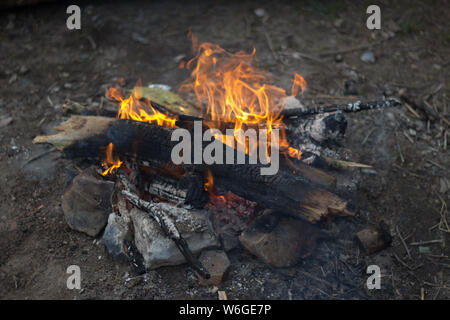 Ein kleines Lagerfeuer aus Zweigen und Ästen mit Felsen in der Umgebung Stockfoto