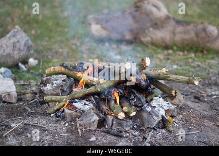 Ein kleines Lagerfeuer aus Zweigen und Ästen mit Felsen in der Umgebung Stockfoto