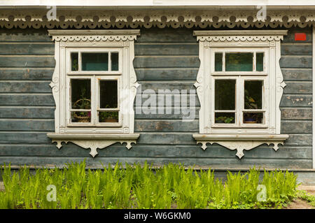 Abgeschält, lackiert, Holzfassade mit zwei Fenstern eines Hauses in einem Park in Bialowieza, Polen Stockfoto