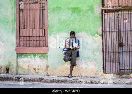 Kubanische Mann steht lehnte sich gegen die Wand eines Gebäudes entlang einer Straße, Havanna, Kuba Stockfoto
