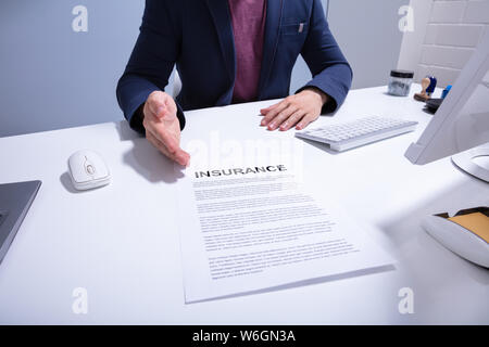 Den mittleren Abschnitt eines Geschäftsmannes, Versicherung Dokument über Weiß Schreibtisch im Büro Stockfoto