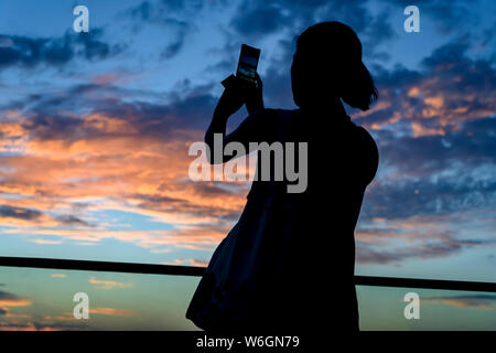 Silhouette einer Frau fotografieren der Sonnenuntergang mit einem Smart Phone, Havanna, Kuba Stockfoto