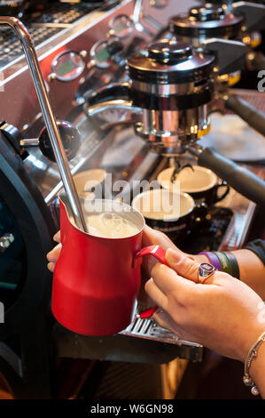 Warme Milch für den italienischen Cappuccino, mit Dampf, bei der Espressomaschine, Stockfoto