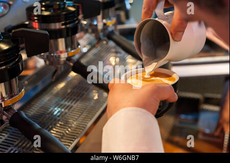 Puoring Milch in eine Tasse, die Vorbereitung von italienischen Cappuccino, mit professionellen Espressomaschine Stockfoto