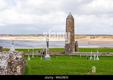 Turm und Grabsteine mit Fluss Shannon im Hintergrund, Clonmacnoise, County Offaly, Irland Stockfoto