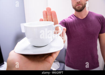 Close-up In eines Mannes Hand ablehnen, Tasse Kaffee angeboten durch Person Stockfoto