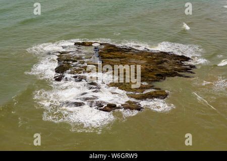 Antenne drone Blick auf die Wellen gegen die Felsen neben einem Leuchtturm brechen Stockfoto