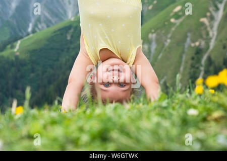 Kleine Mädchen stehen auf Ihren Kopf in die Berge Stockfoto