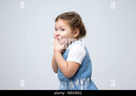 Kleines Mädchen Mund mit den Händen warten auf Geschenk überrascht abgedeckt Stockfoto