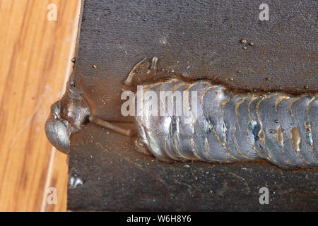 Die Kehlschweißung wird mit der MAG-Methode gelegt. Fehler in Stahl Verbindungen mittels Arc Welding. Der dunkle Hintergrund. Stockfoto