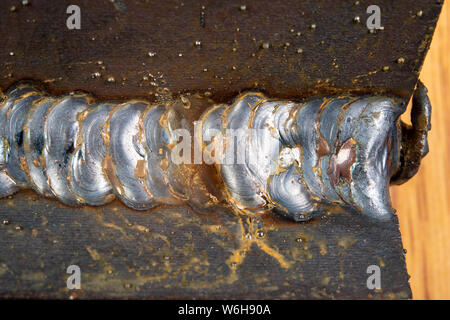 Die Kehlschweißung wird mit der MAG-Methode gelegt. Fehler in Stahl Verbindungen mittels Arc Welding. Der dunkle Hintergrund. Stockfoto