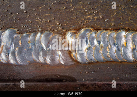 Die Kehlschweißung wird mit der MAG-Methode gelegt. Fehler in Stahl Verbindungen mittels Arc Welding. Der dunkle Hintergrund. Stockfoto