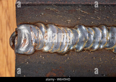 Die Kehlschweißung wird mit der MAG-Methode gelegt. Fehler in Stahl Verbindungen mittels Arc Welding. Der dunkle Hintergrund. Stockfoto