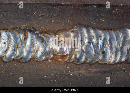 Die Kehlschweißung wird mit der MAG-Methode gelegt. Fehler in Stahl Verbindungen mittels Arc Welding. Der dunkle Hintergrund. Stockfoto