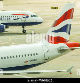 Der Flughafen London Gatwick, ENGLAND - April 2019: Schwanzflosse eines British Airways Jet am Flughafen Gatwick mit einem anderen Flugzeug im Hintergrund Stockfoto