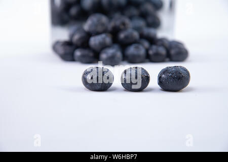 Leckere Heidelbeeren - Haufen frisch geernteten reifen Heidelbeeren auf einem weißen Hintergrund - große, süße nass Blaubeeren auf einem weißen Tisch - Close-up Stockfoto