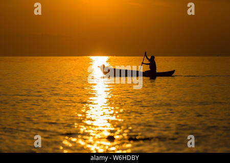 Einbaum fischer Silhouette gegen Orange Sonnenaufgang am Lake Malawi, die Sonne Glitzern auf dem See, Süd-Ost-Afrika Stockfoto