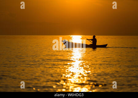 Einbaum fischer Silhouette gegen Orange Sonnenaufgang am Lake Malawi, die Sonne Glitzern auf dem See, Süd-Ost-Afrika Stockfoto