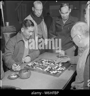 Herz Berg Relocation Center, Heart Mountain, Wyoming. Eine Gruppe von centerites versammeln sich um zwei. . .; Umfang und Inhalt: Der vollständige Titel für dieses Foto liest: Herz Berg Relocation Center, Heart Mountain, Wyoming. Eine Gruppe von centerites versammeln sich um zwei Experten des Zentrums Go Spieler. Das Spiel, im Volksmund als Spiel der militärischen Strategie konzipiert, ist es fast eine Schlacht des scharfen Verstand, obwohl auch diese von einem sechs Jahre alten Jungen, der vor kurzem 13 Spieler gleichzeitig spielen an diesem Zentrum frustriert besiegt wurde. Stockfoto