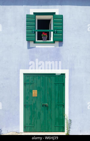 Cute retro Purple House mit grünem Holz- Fenster mit Fensterläden und Blumen im Topf und grüne Tür mit weißen Rahmen. Stockfoto