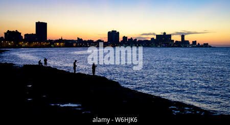 Silhouetten der Fischer entlang des Malecon mit einer Silhouette Skyline in der Dämmerung, Havanna, Kuba Stockfoto