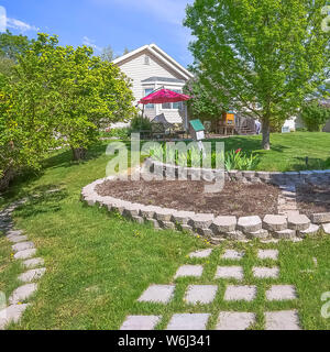 Quadratisch angelegten begrünten Hof des Hauses mit üppigen Bäumen und dekorativen Beton Steine Stockfoto