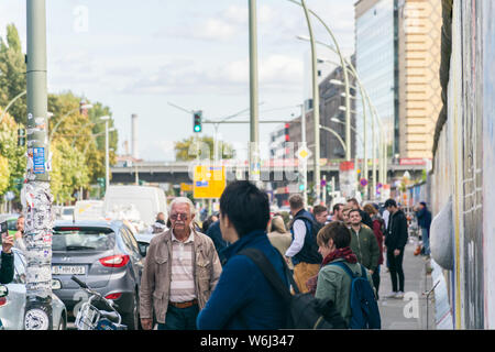 BERLIN, DEUTSCHLAND - 26. September 2018: Stadtbild eines langen Gehweg mit Autos, Gebäude und Touristen zu Fuß durch die Berliner Mauer an der Ostseite Stockfoto