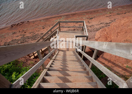 Eine Treppe Flug aus Holz, die zum roten Lehm Strand unten Stockfoto