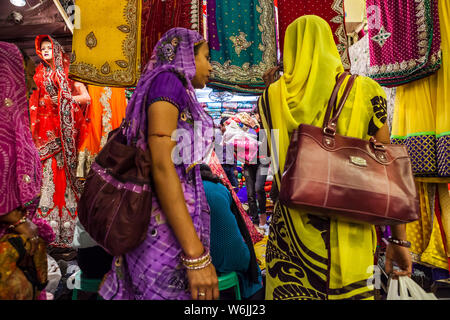 Eine Frau schaut sich die Kamera in einem Frauen Spaziergang durch die vielen sari Geschäfte in einer verkrampften besetzt sari Markt in Jaipur, Rajasthan, Indien. Stockfoto