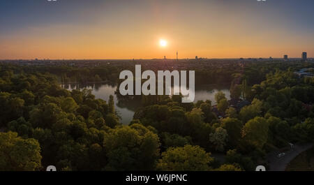 Ein herrlicher Sonnenuntergang über einem See, umgeben von Bäumen in München, Bayern. Stockfoto